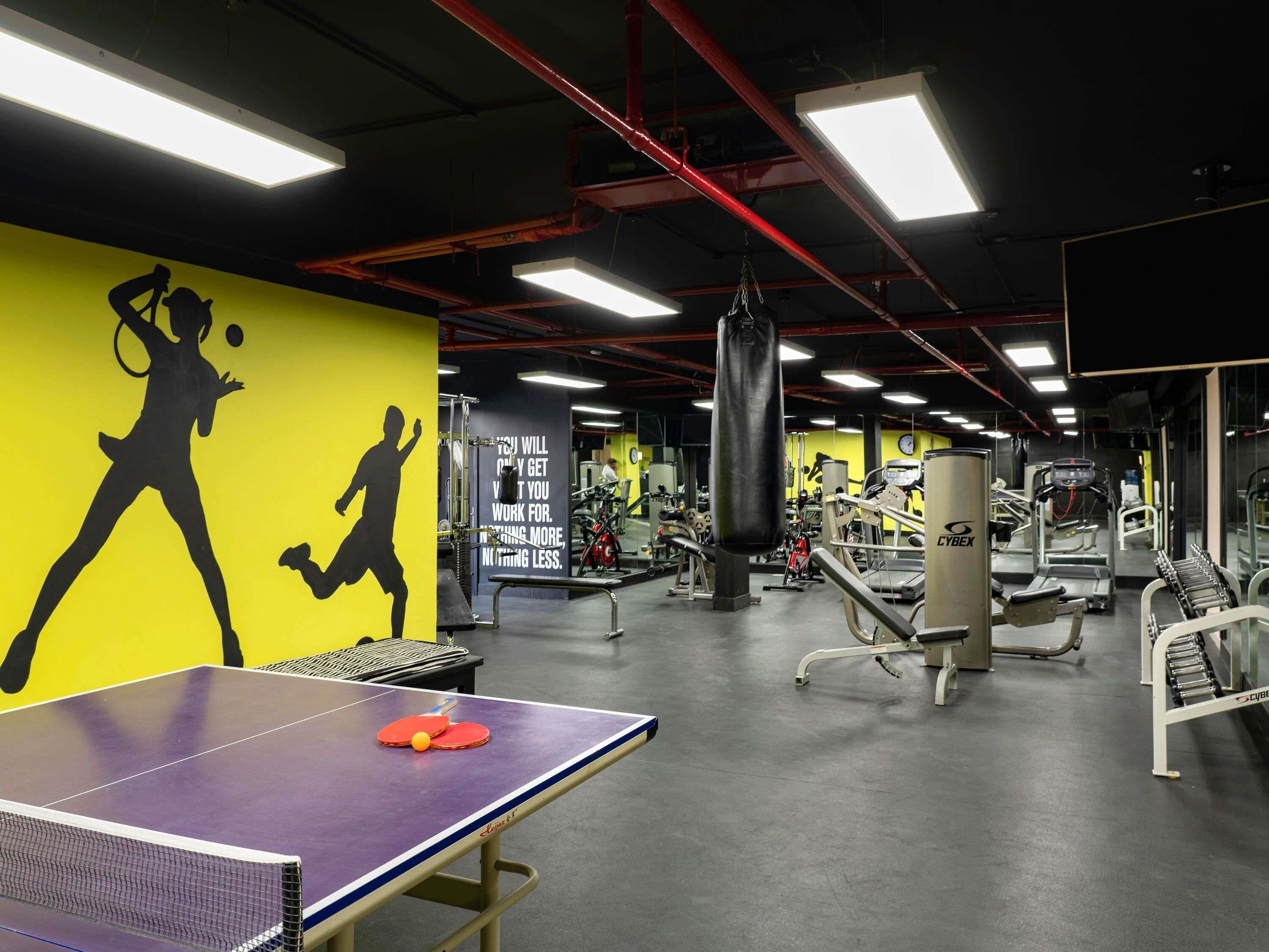 A gym with exercise equipment, a ping pong table, and motivational wall art.