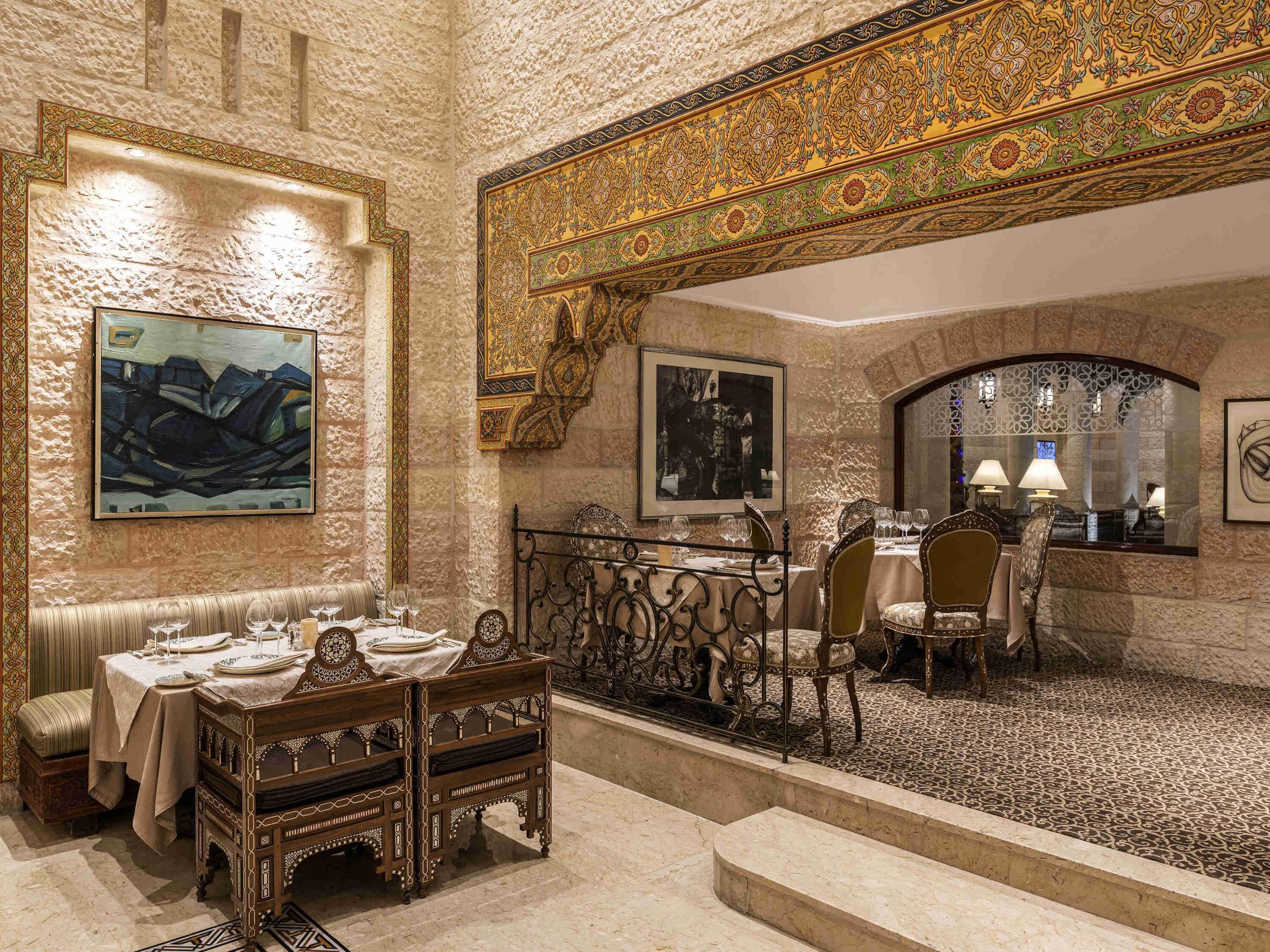 A dining area with ornate furniture, a high ceiling, and decorative wall patterns.