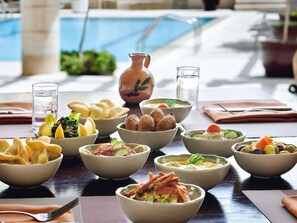 A dining table with various dishes, a pitcher, and a glass of water. - Mövenpick Resort Petra (Wadi Musa)