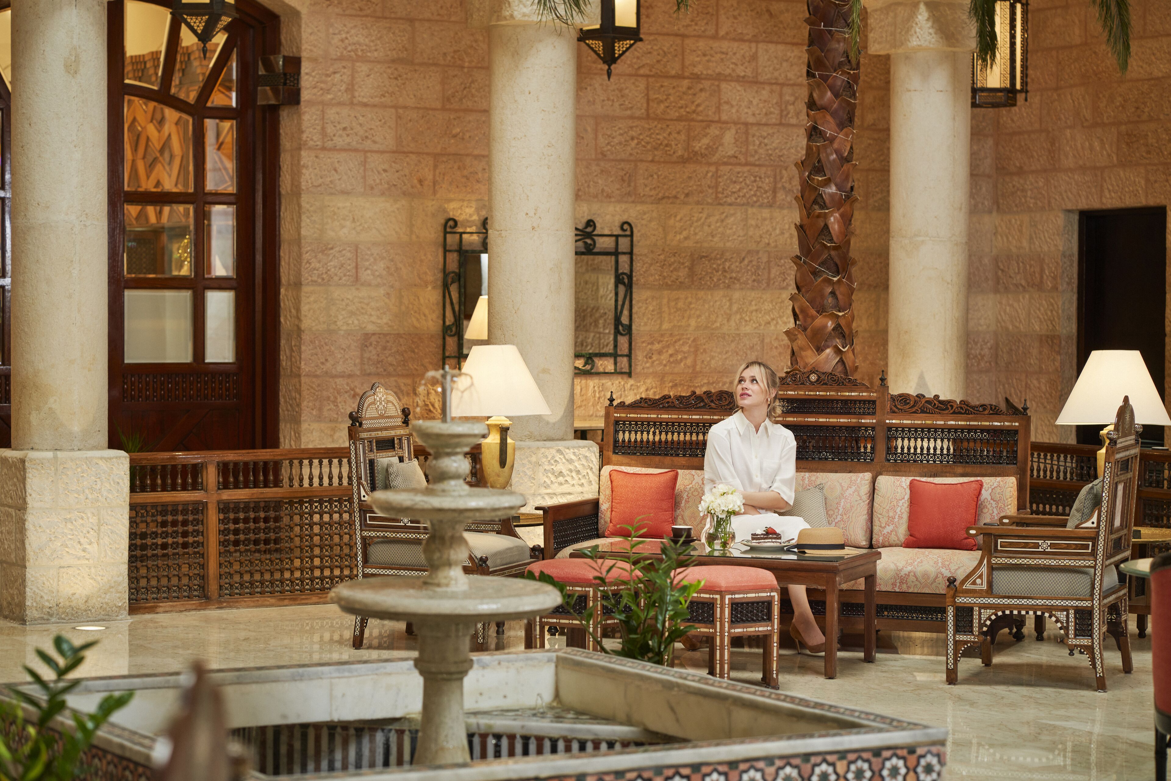 A lobby with a fountain, seating area, and a large wooden door.