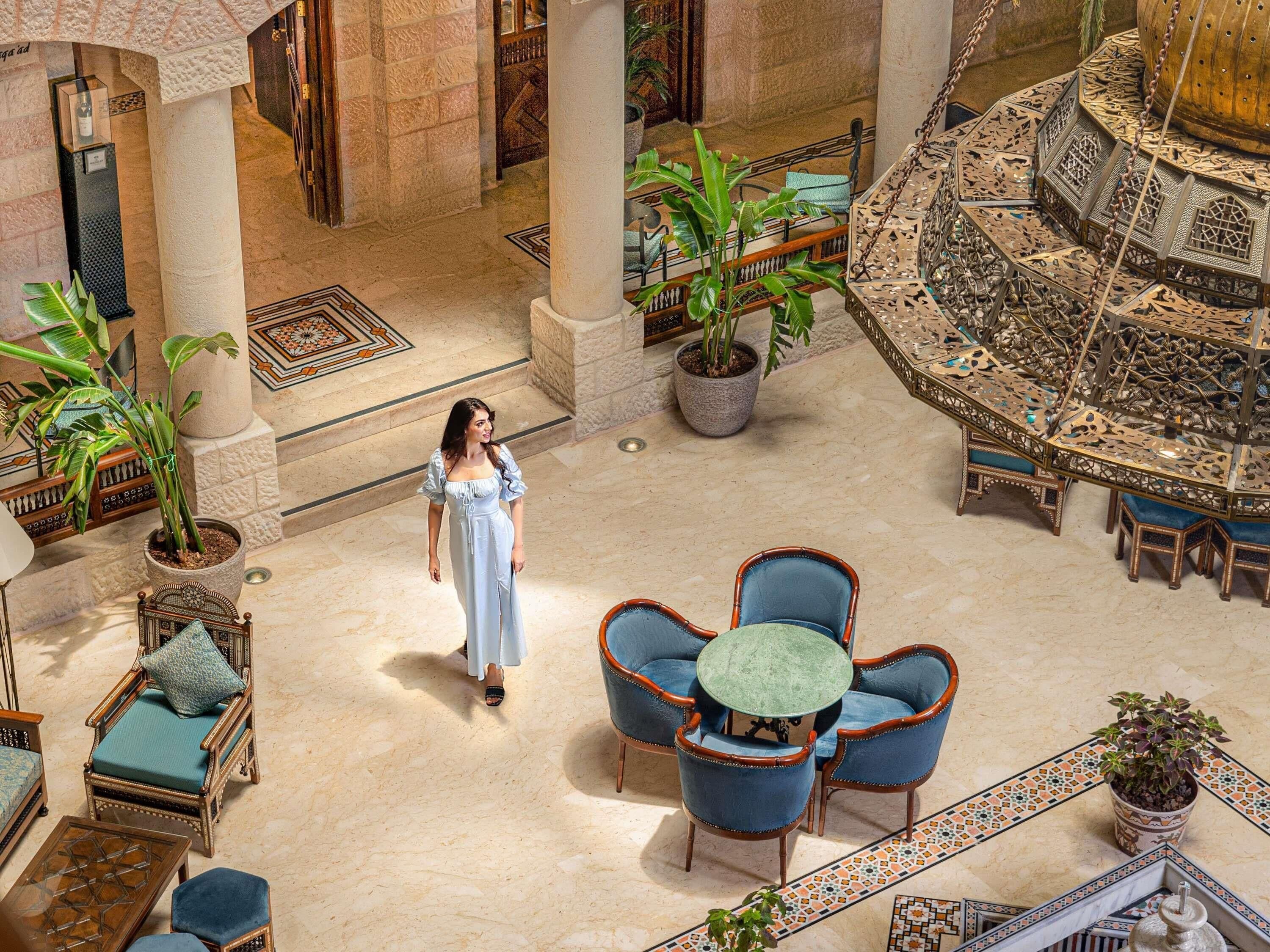Un hall d’entrée spacieux avec un espace salon central, des plantes en pot et une fontaine décorative.