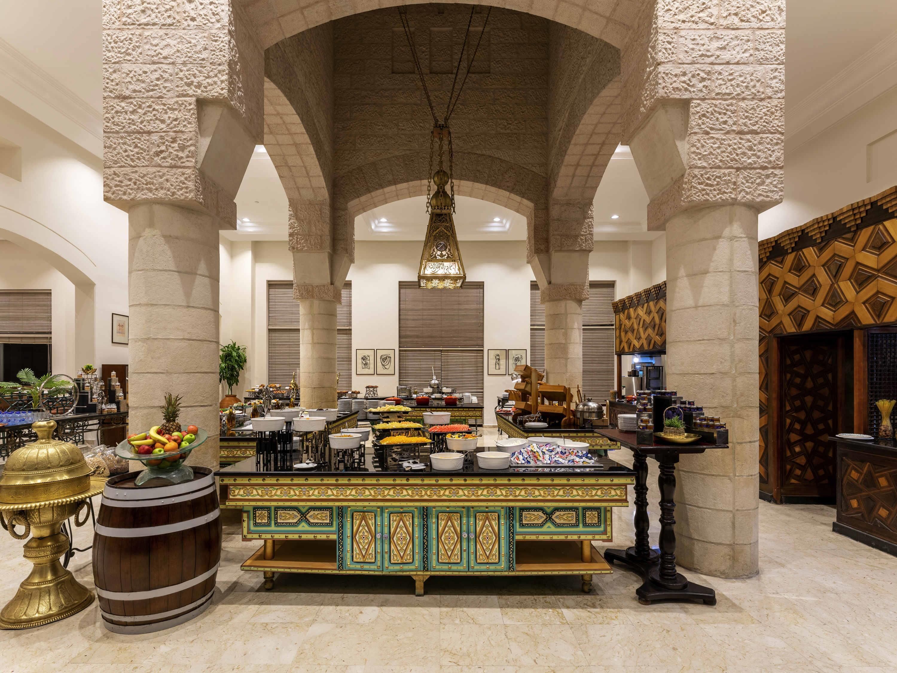 A spacious lobby with a central buffet area, stone columns, and a decorative ceiling.