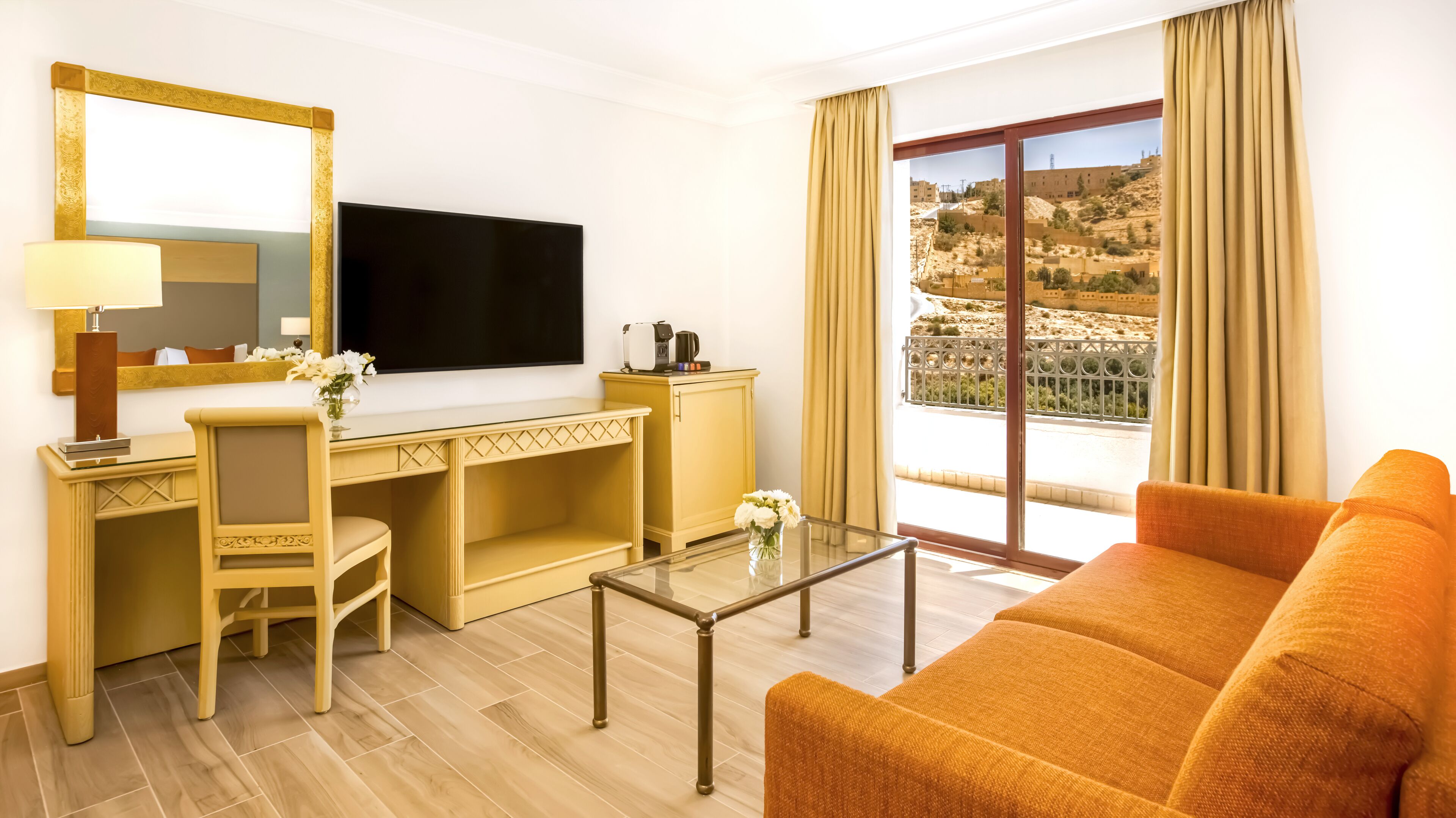 Ett hotellrum med ett skrivbord, en stol, en TV och en soffa.