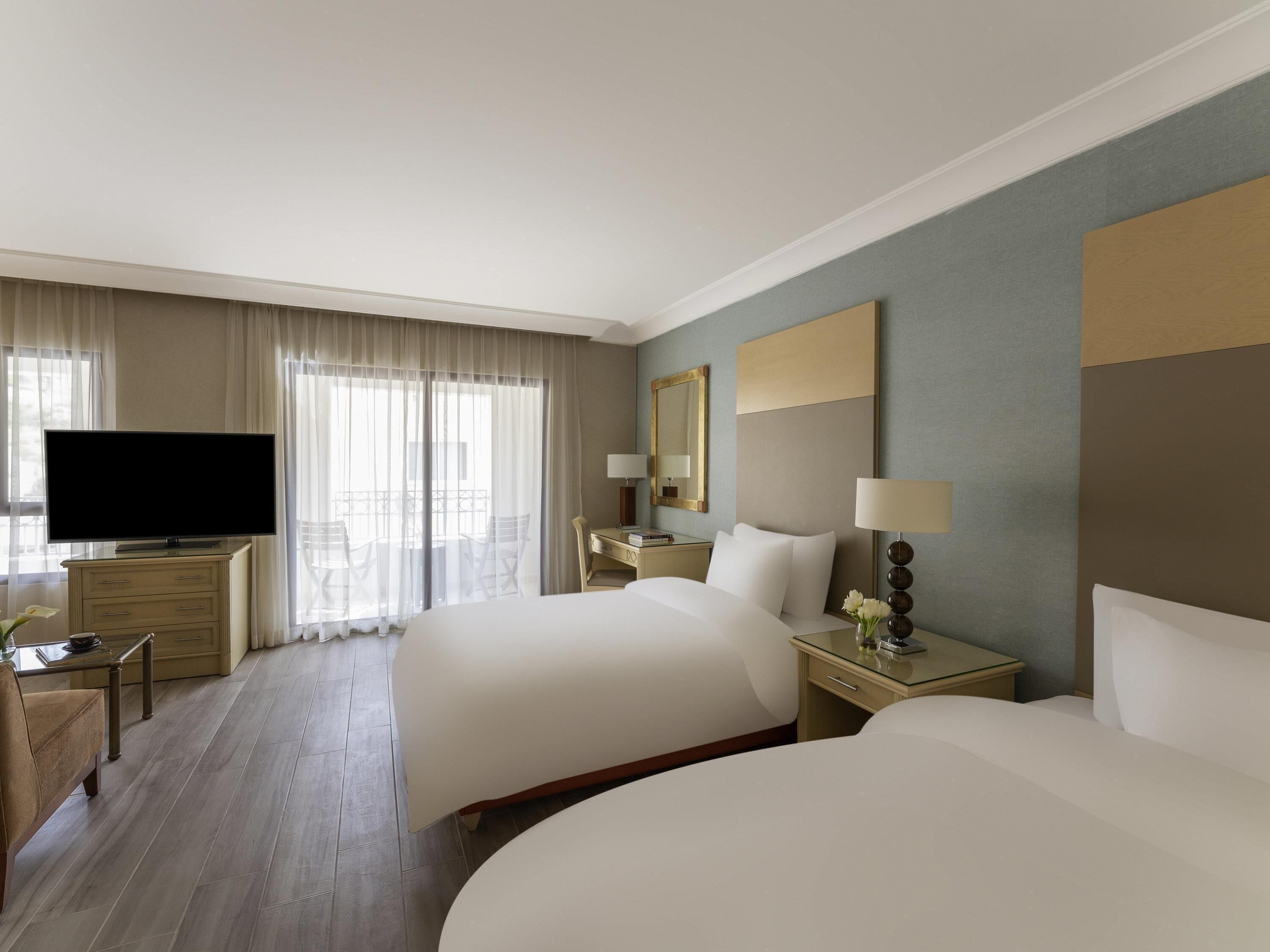 Habitación de hotel con dos camas, televisión, escritorio y silla.