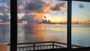 A view from a balcony overlooking a calm sea at sunset with clouds reflecting on the water. - Aquarius Beach Tower (Saipan)