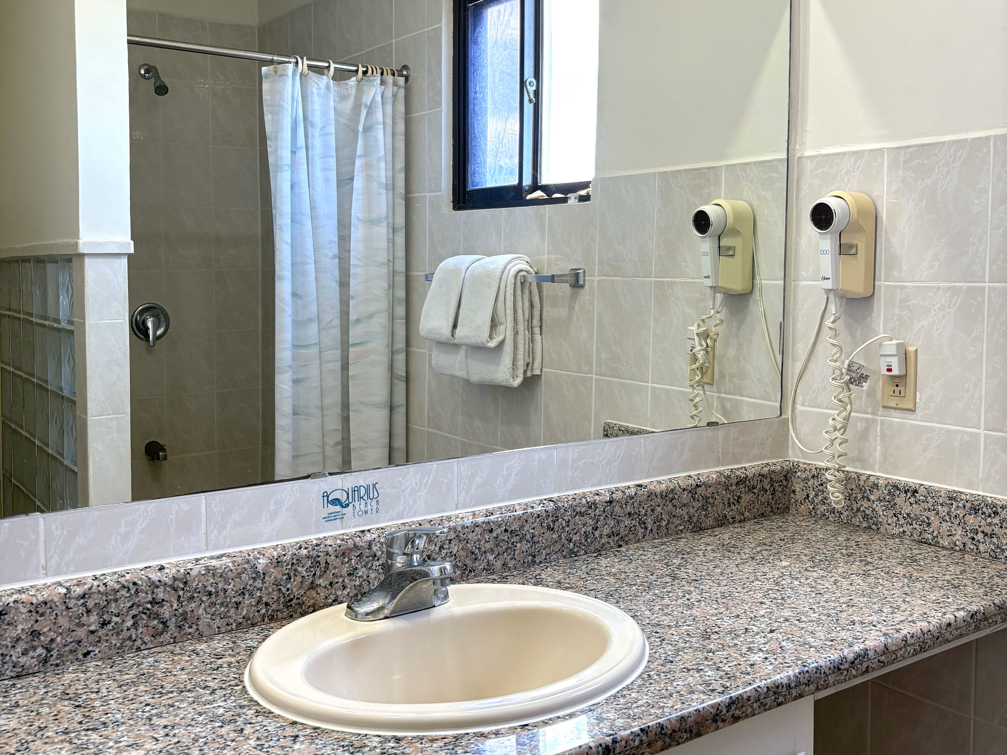 A bathroom with a granite countertop, a sink, a shower with a glass door, a towel rack, and a mirror.