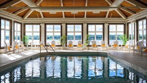 An indoor swimming pool with a wooden ceiling and large windows offering a view of the outdoors. - Rodd Miramichi (Miramichi)