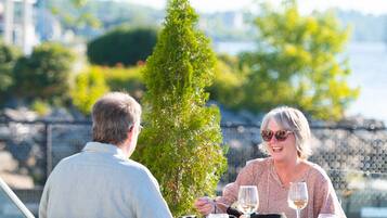 A couple dining at an outdoor table with a view of a bridge and greenery.
