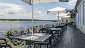 A waterfront restaurant with outdoor seating, tables with umbrellas, and a view of the water. - Rodd Miramichi (Miramichi)