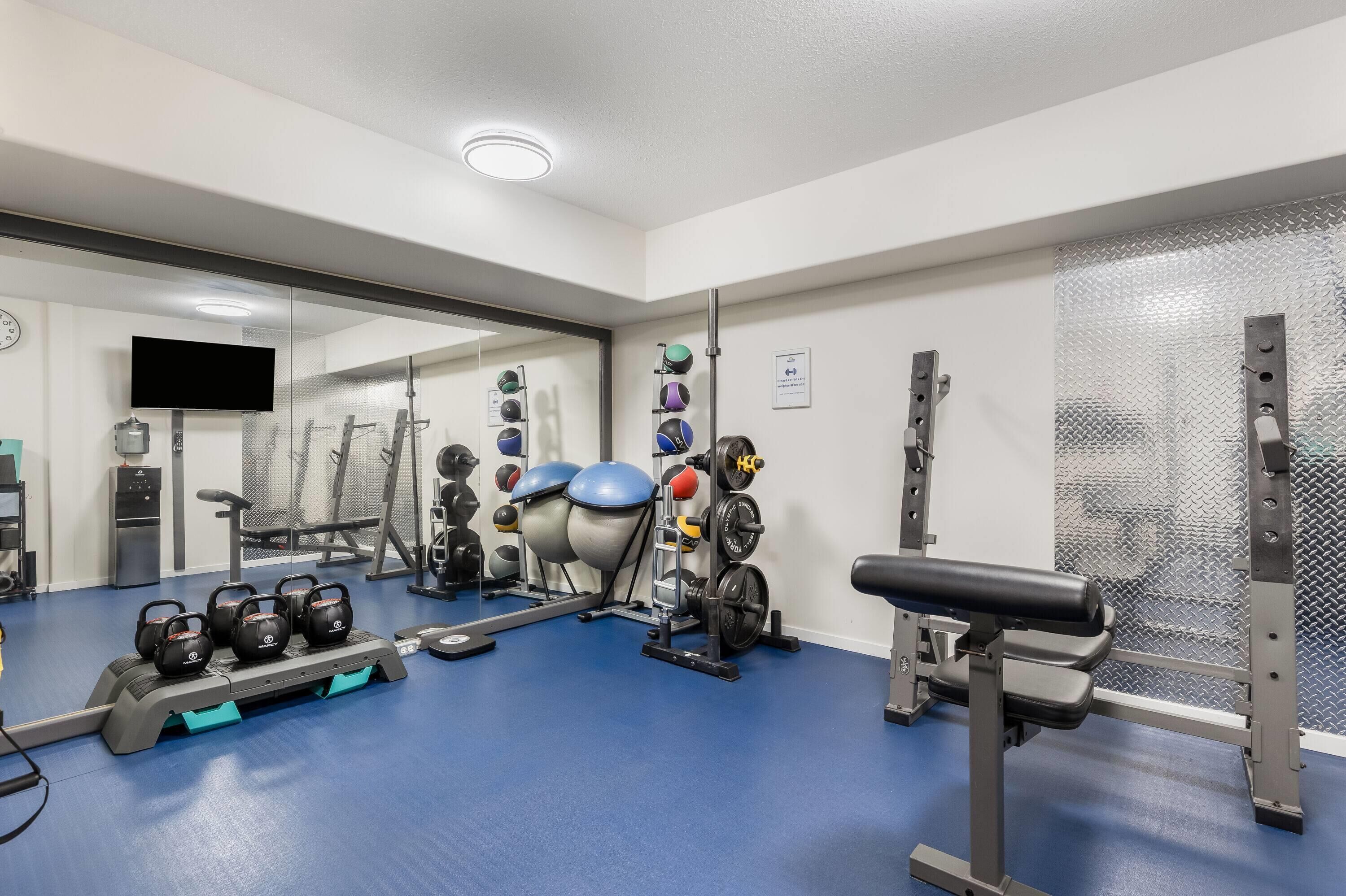 A gym with exercise equipment, a mirror, and a television.