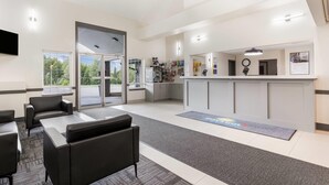 A modern hotel lobby with a reception desk, seating area, and a view of the outdoors. - Days Inn by Wyndham Valemount (Valemount)