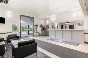 A modern hotel lobby with a reception desk, seating area, and a view of the outdoors. - Days Inn by Wyndham Valemount (Valemount)