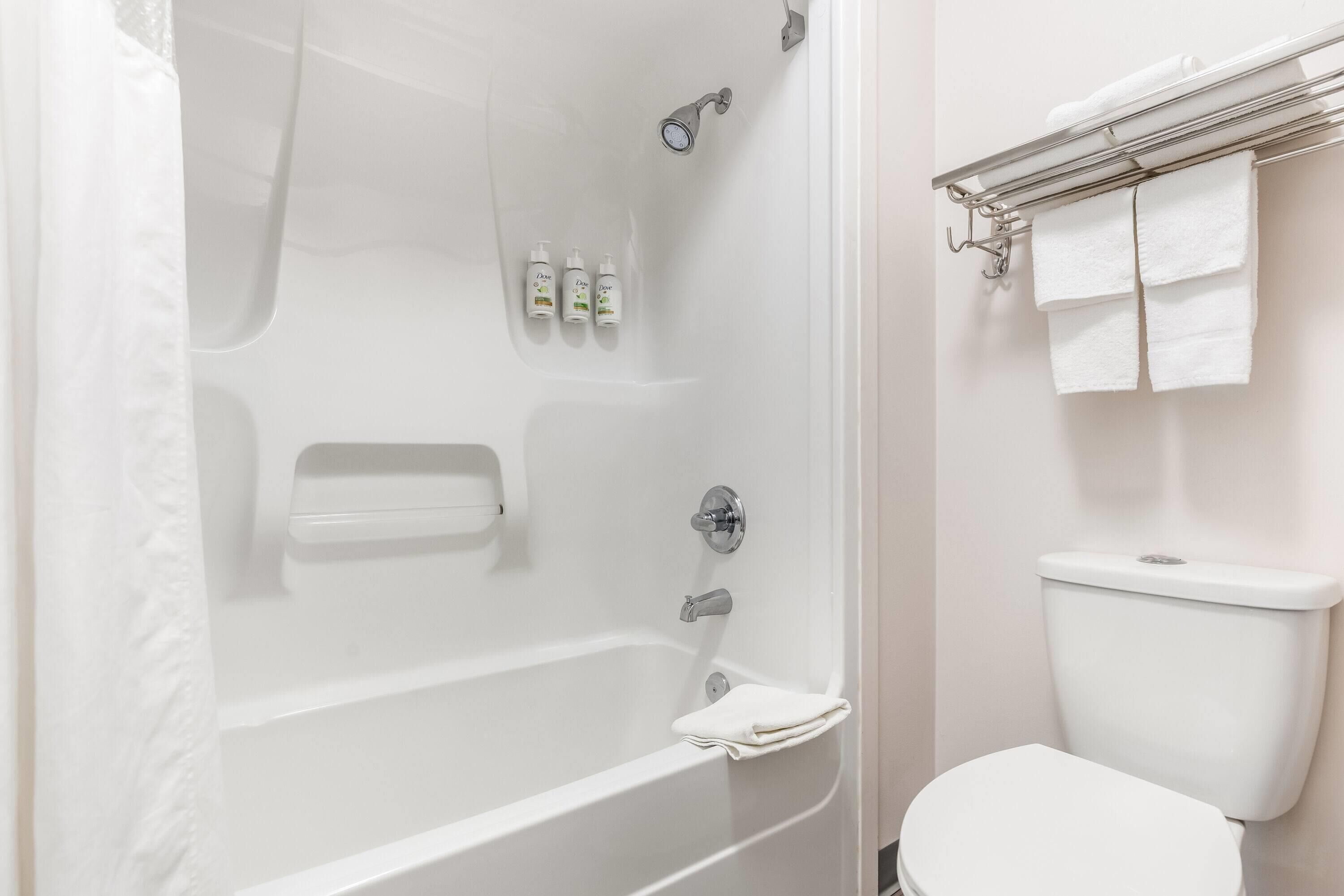 A bathroom with a bathtub, toilet, and a towel rack with towels.