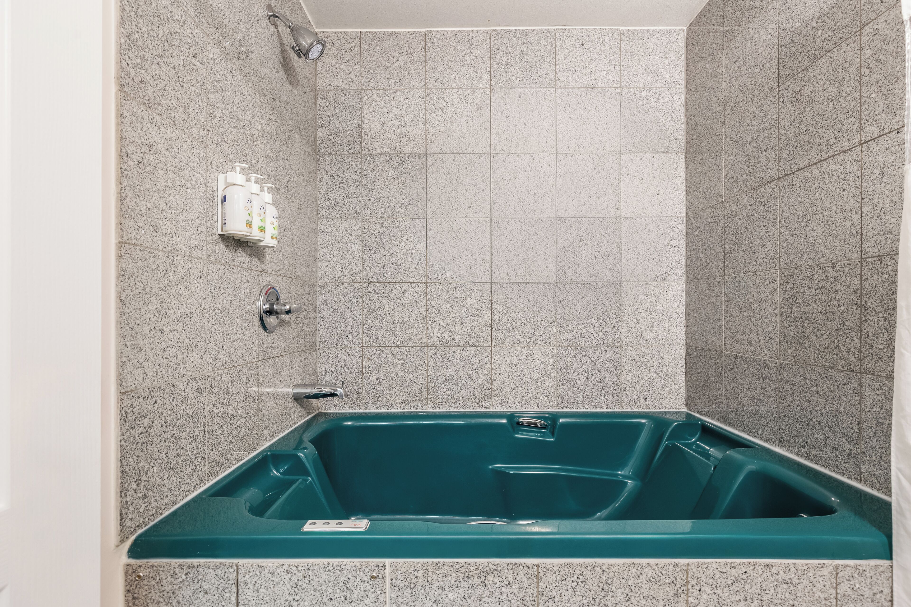Un baño con bañera, ducha y dispensador de artículos de aseo.