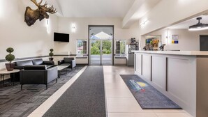 A hotel lobby with a reception desk, seating area, mounted moose head, and a view through the door. - Days Inn by Wyndham Valemount (Valemount)