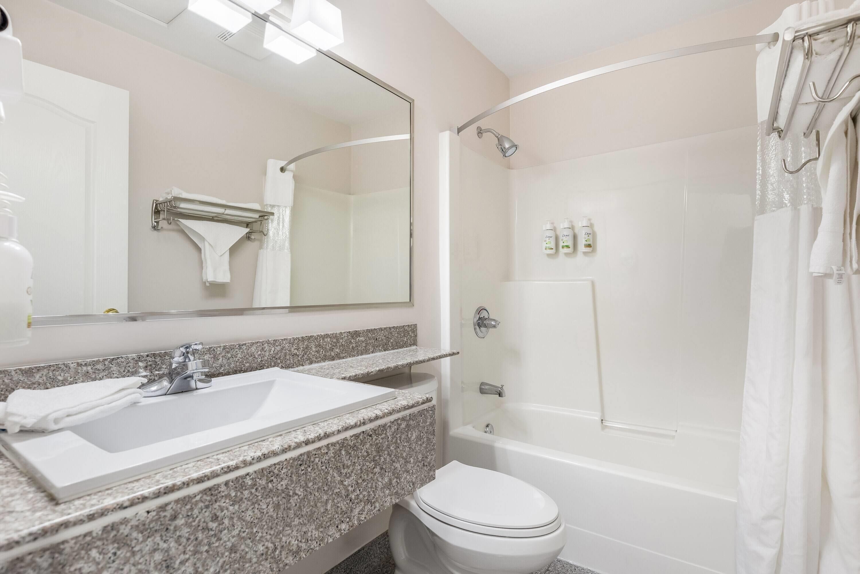 A bathroom with a white sink, mirror, and shower.