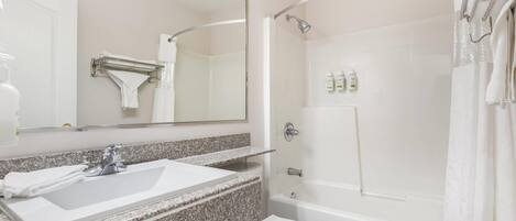 A bathroom with a white sink, mirror, and shower.