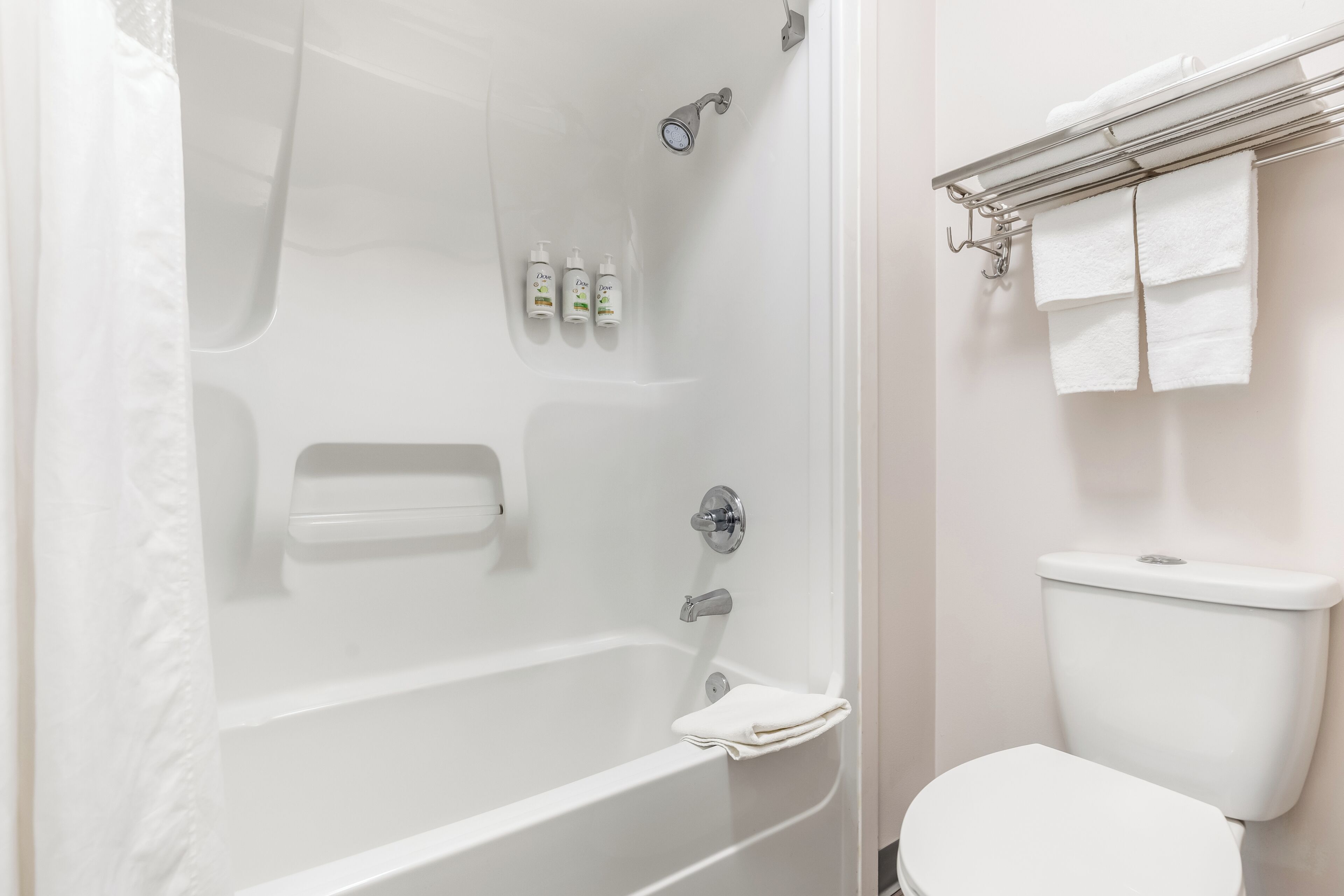 A bathroom with a bathtub, toilet, and a towel rack.