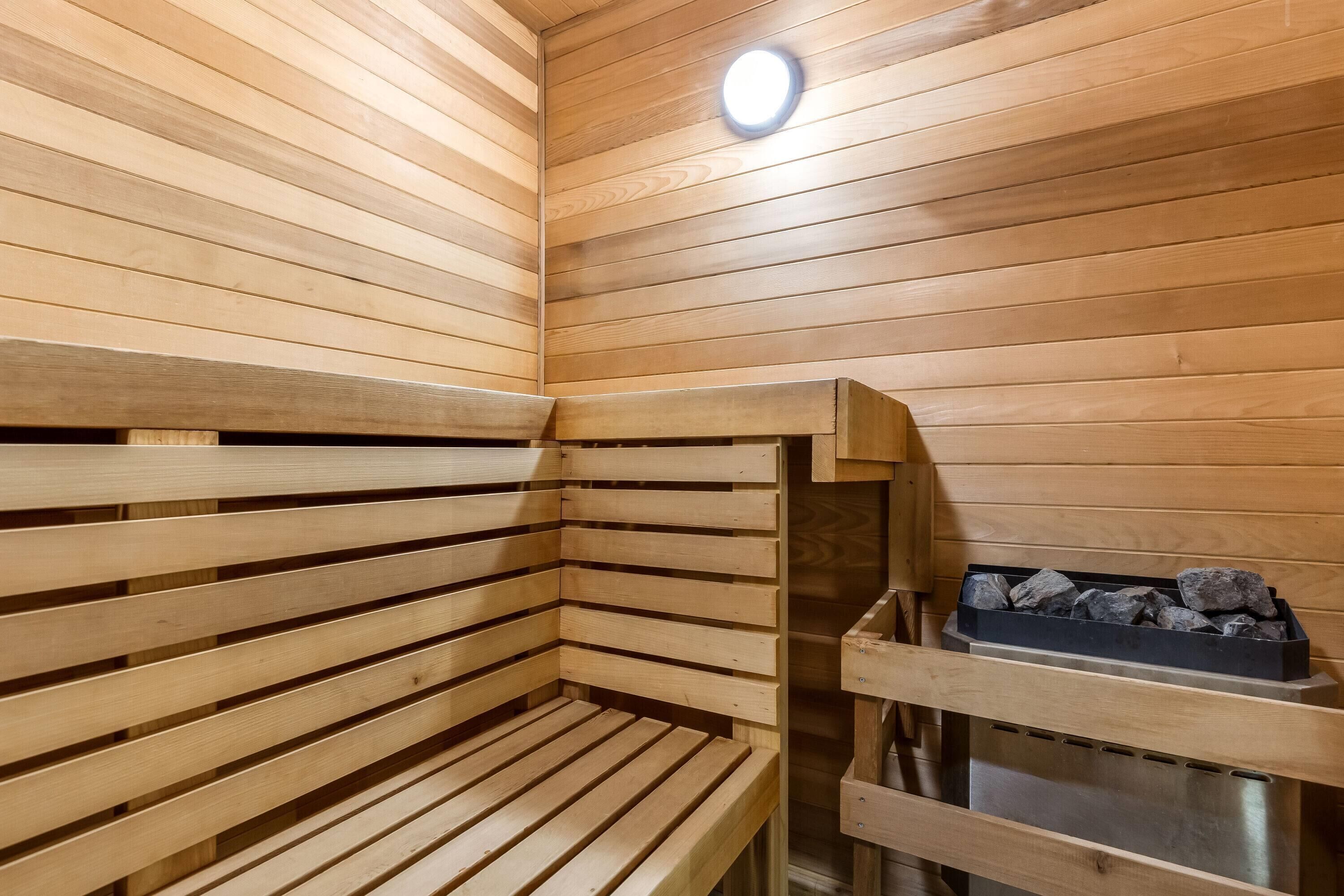 A sauna with wooden benches and a metal rack holding stones.