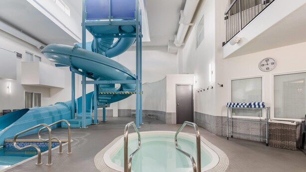 An indoor swimming pool with a water slide, a sauna area, and a clock on the wall. - Days Inn by Wyndham Valemount (Valemount)