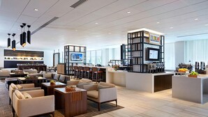 Un hall d’hôtel moderne doté d’un bar, de différents espaces de détente et d’un grand écran.
