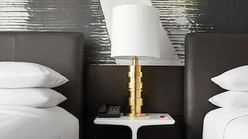 A hotel room with two beds, a nightstand with a lamp, and a wall mural.