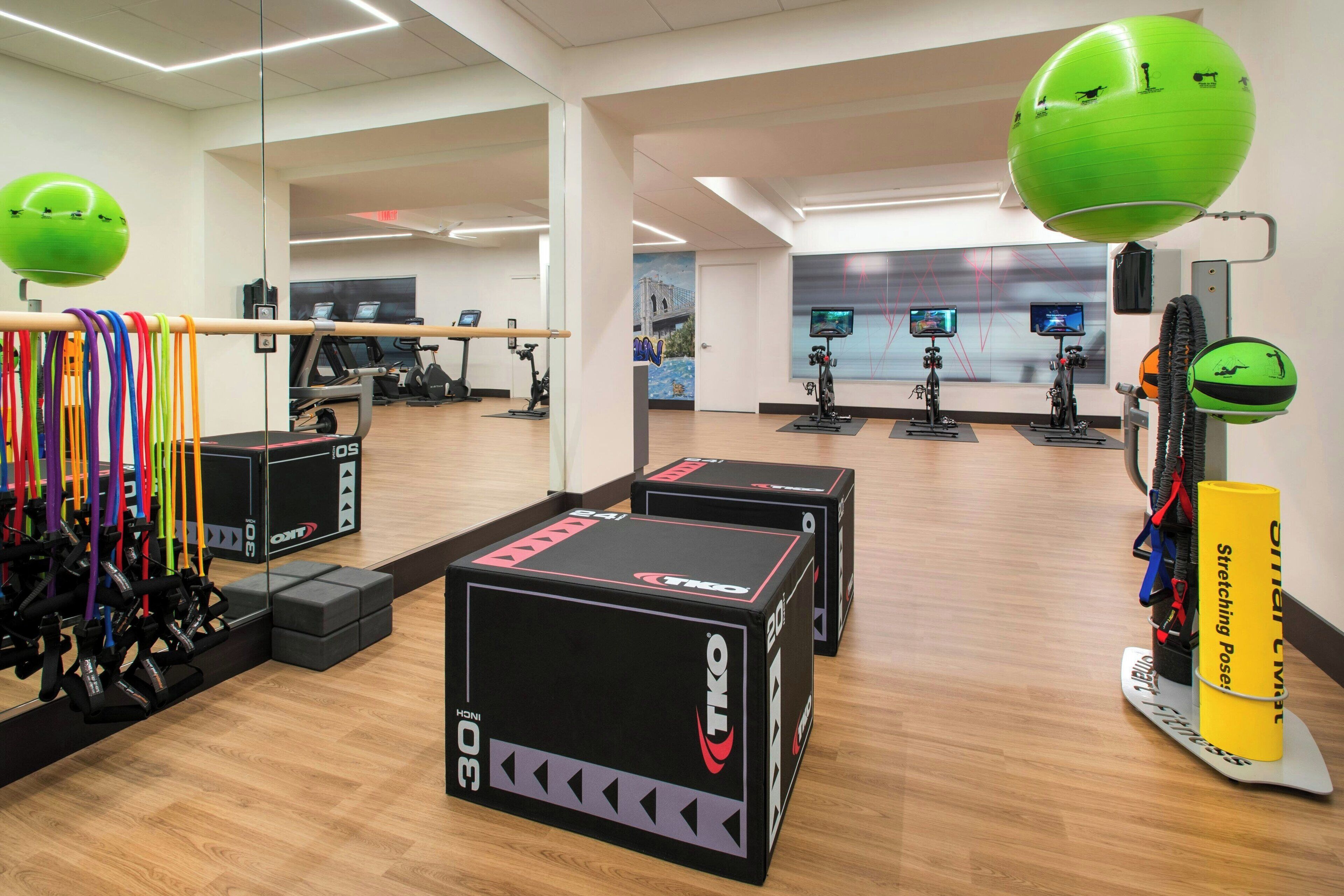A gym with exercise equipment, mirrors, and a large mirror wall.