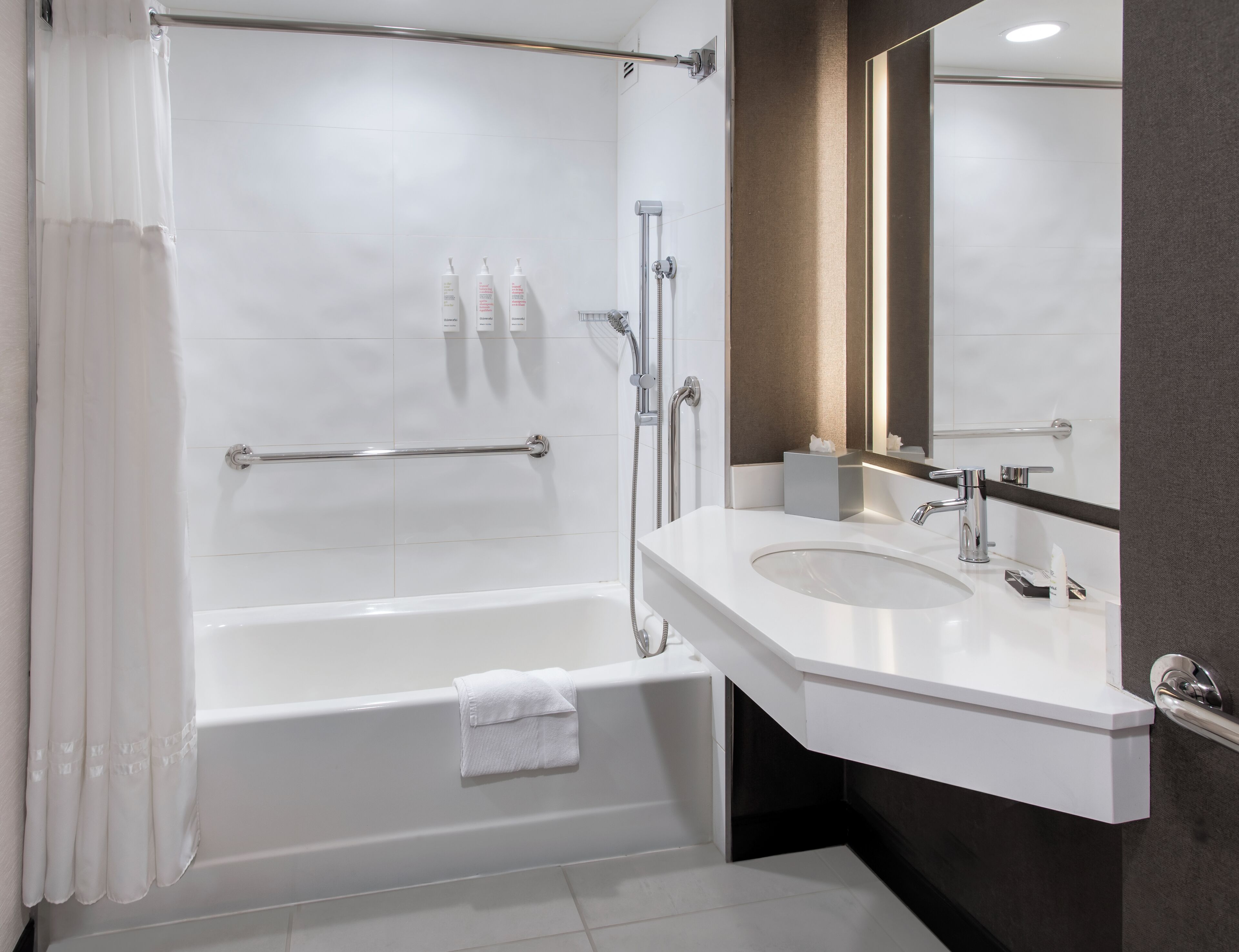 A modern bathroom with a bathtub, a shower, a vanity with a sink, and a mirror.