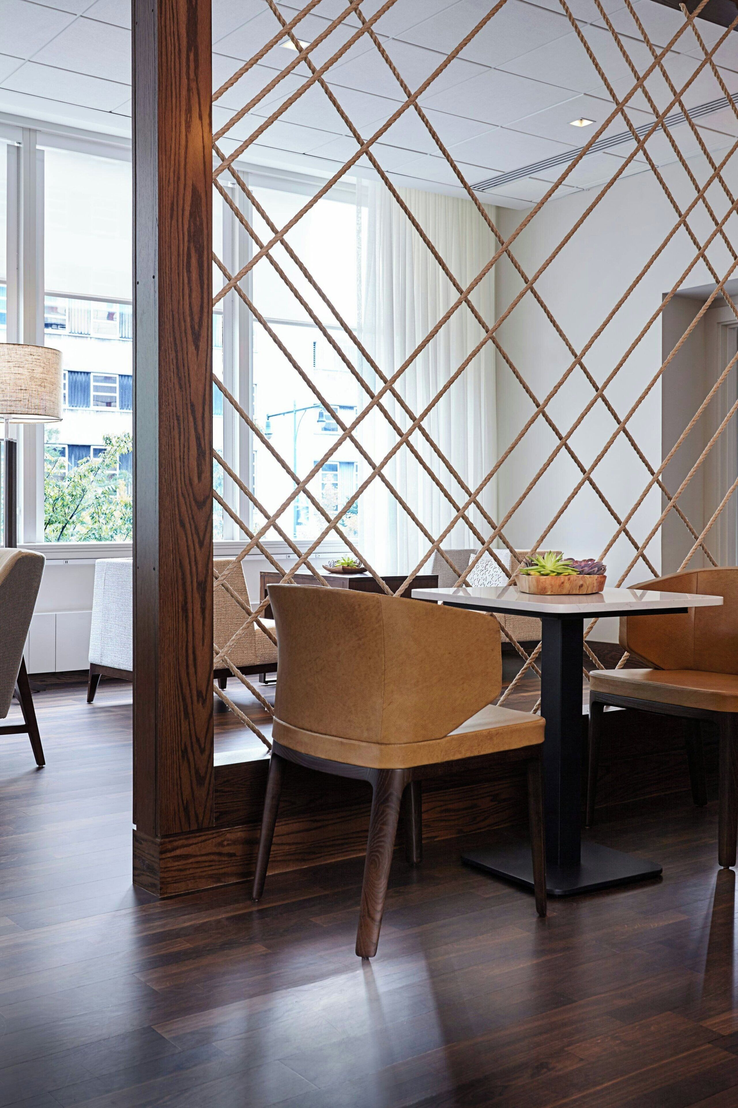 A modern dining area with a wooden partition, a round table, and two chairs.