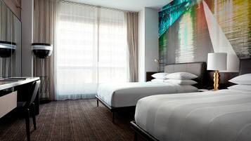 A hotel room with two beds, a desk, and a large abstract painting on the wall.