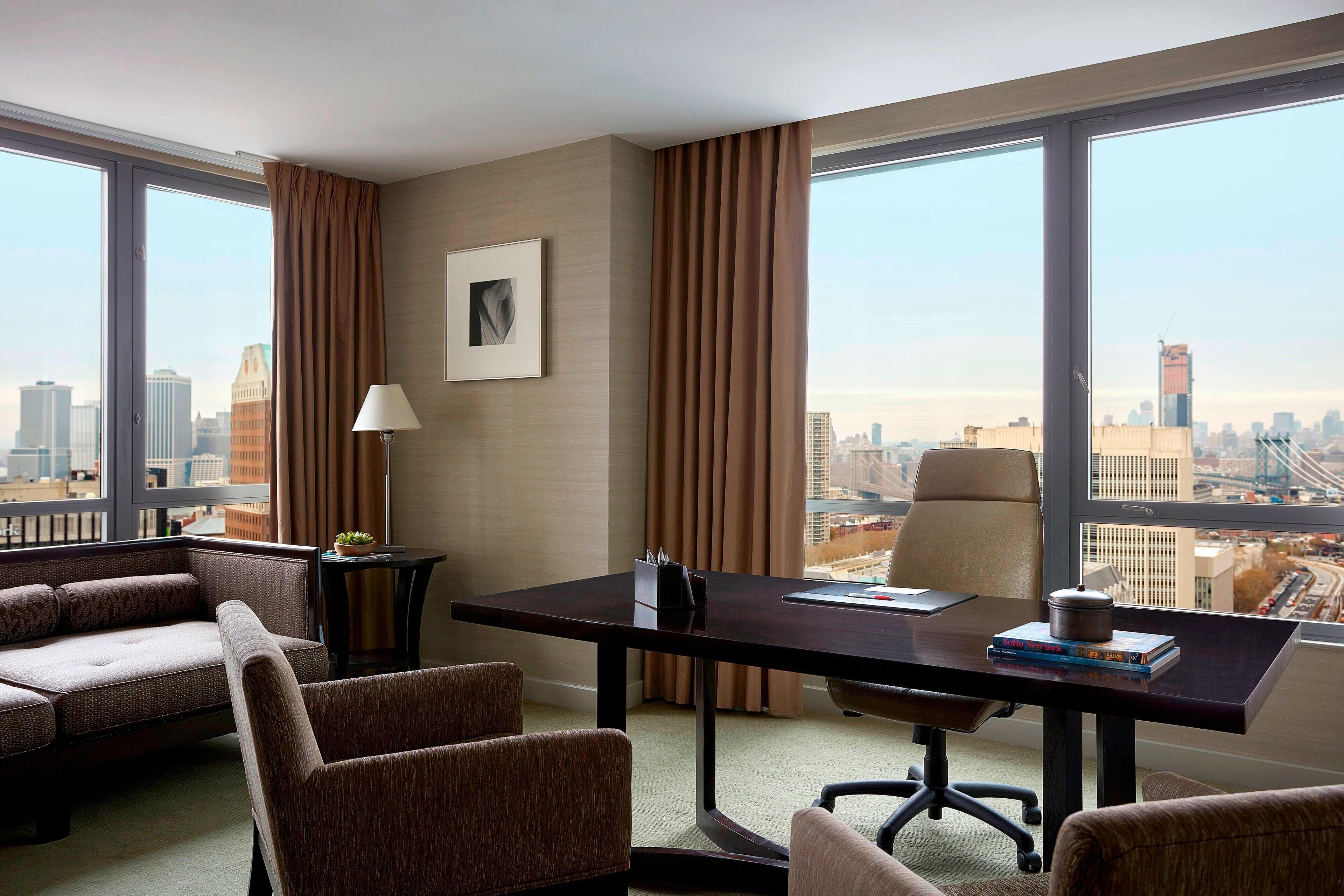 Una habitación de hotel moderna con un escritorio grande, asientos cómodos y vistas a la ciudad.
