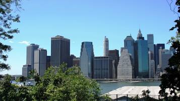 A city skyline with modern high-rise buildings, a body of water, and a fenced area in the foreground.