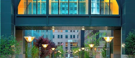 Un bâtiment moderne doté d’une façade en verre, d’une galerie couverte et d’espaces de détente en plein air.