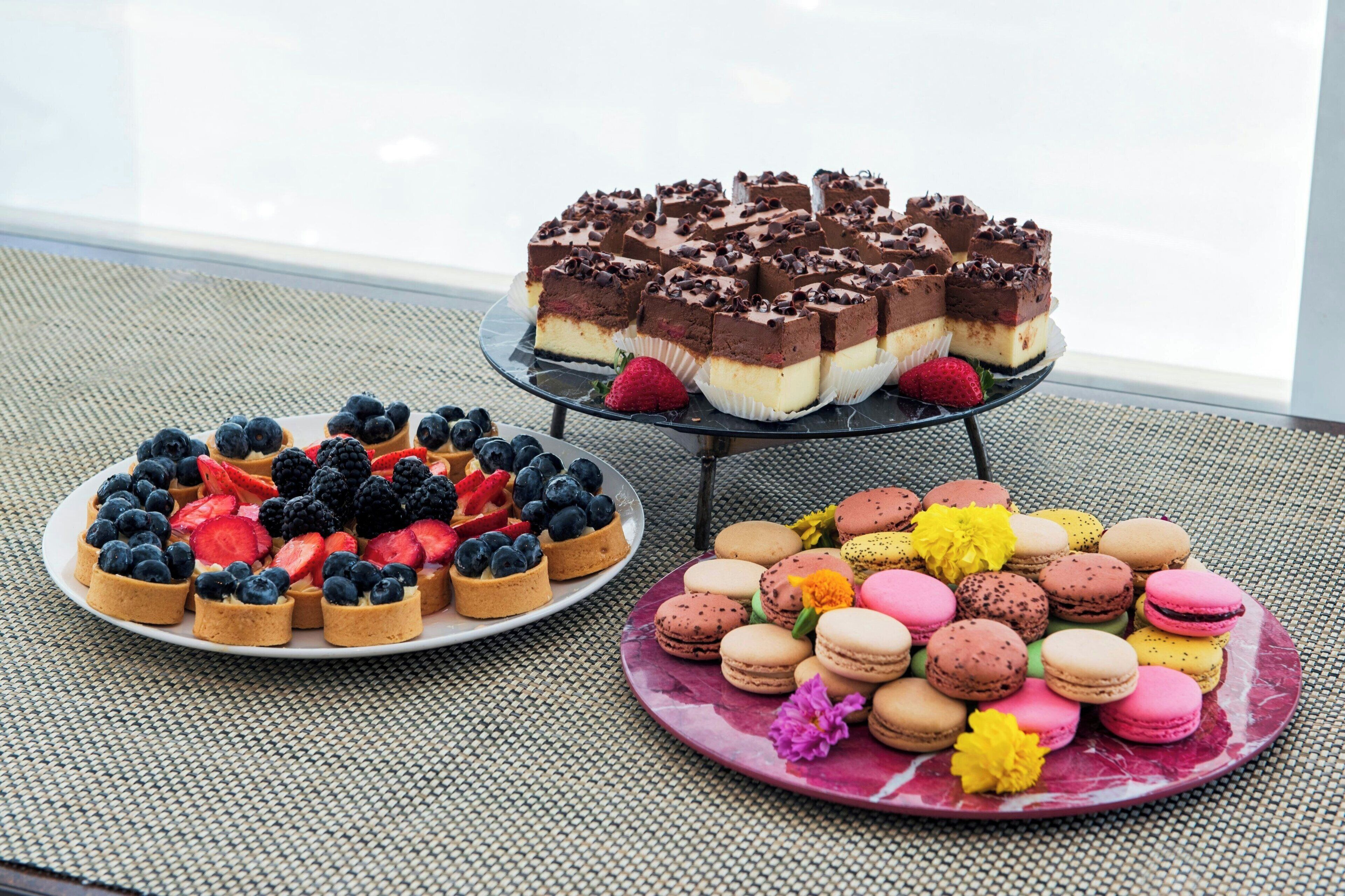 A dessert display with various pastries and macarons on plates.