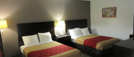 Habitación de hotel con dos camas, cada una con cabecero, mesitas de noche, lámparas y una colcha roja y beige.