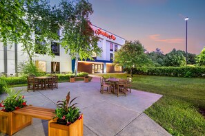 A hotel with outdoor seating and a garden area.