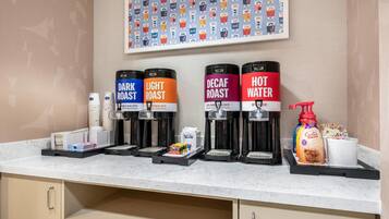 Una estación de café con cuatro dispensadores etiquetados como: TUESTA OSCURA, TUESTA CLARA, DESCAFEINADO y AGUA CALIENTE.