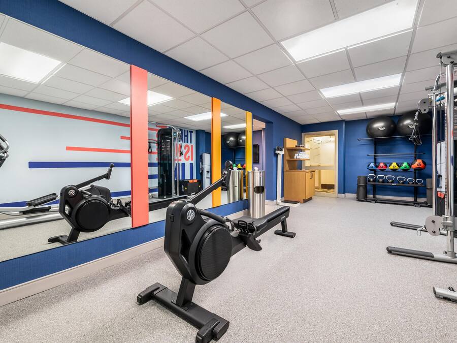 A gym with exercise equipment, a mirror, and a wall with a red and blue design.