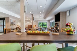 Un amplio comedor con una larga mesa de madera, múltiples sillas y una exhibición de frutas.