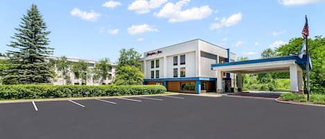 A commercial building with a parking lot, a covered entrance, and an American flag.