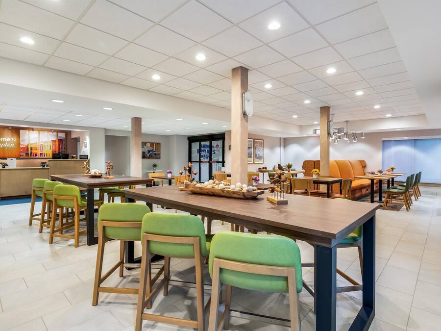 A hotel lobby with a reception desk, seating areas, and a large dining table with chairs.