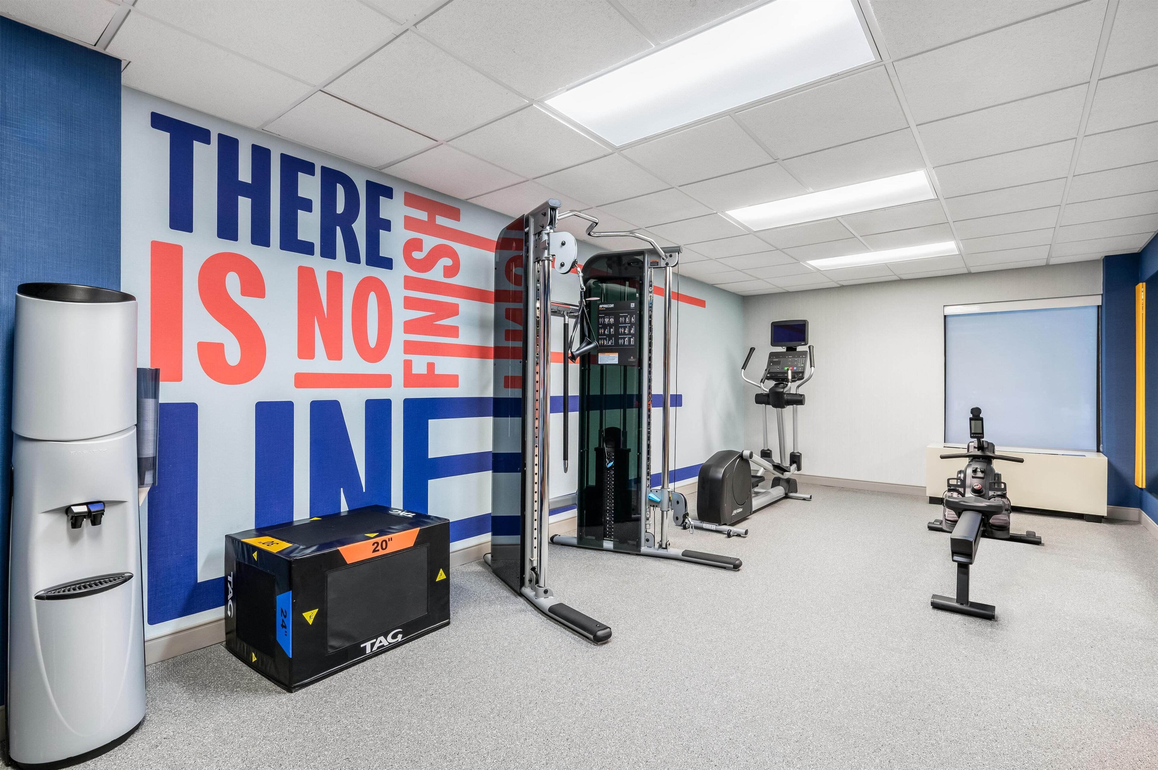 A gym with a motivational wall, exercise equipment, and a water dispenser.