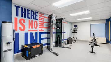 A gym with a motivational wall, exercise equipment, and a water dispenser.