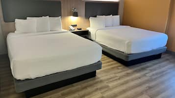 Une chambre d’hôtel avec deux lits, une table de chevet avec une lampe et un téléphone fixé au mur.