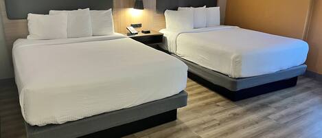 Una habitación de hotel con dos camas, una mesita de noche con lámpara y un teléfono en la pared.