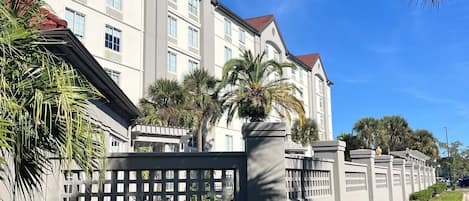 A multi-story hotel with a symmetrical facade, large windows, and a gated entrance.