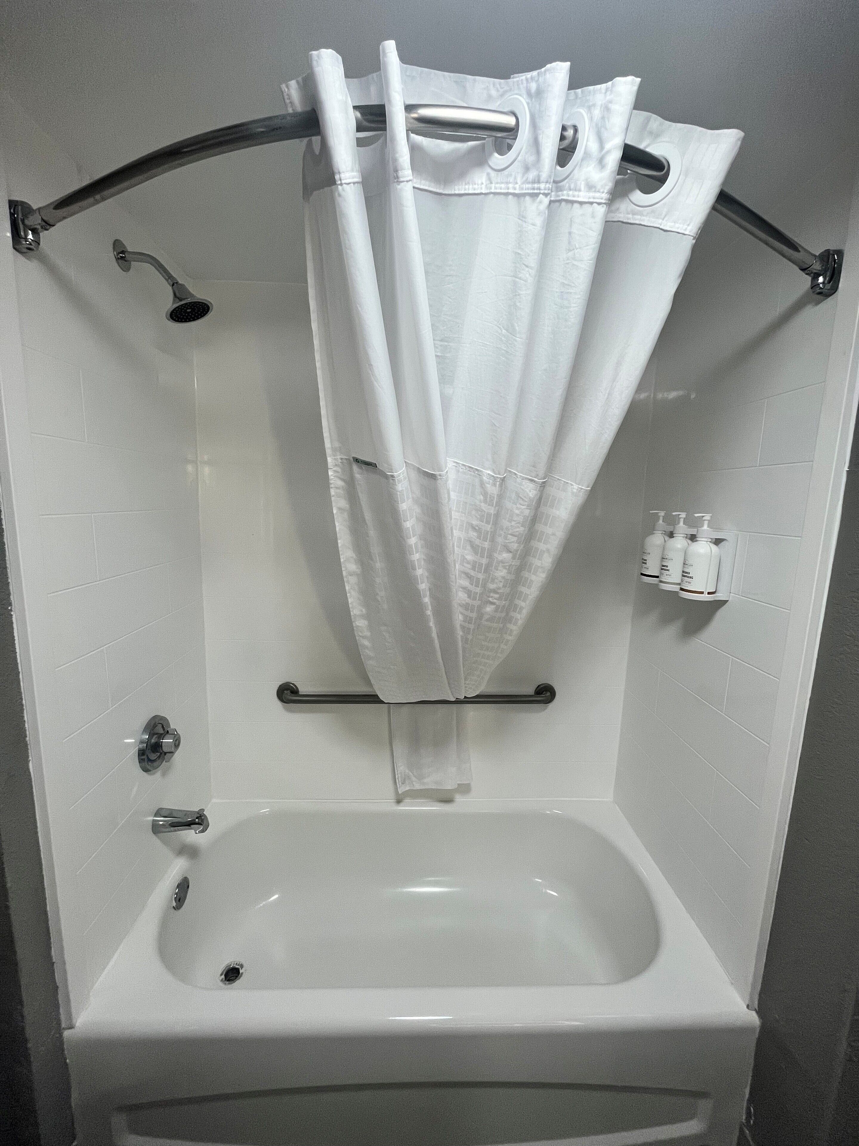 Un baño con bañera, cabezal de ducha y toallero.