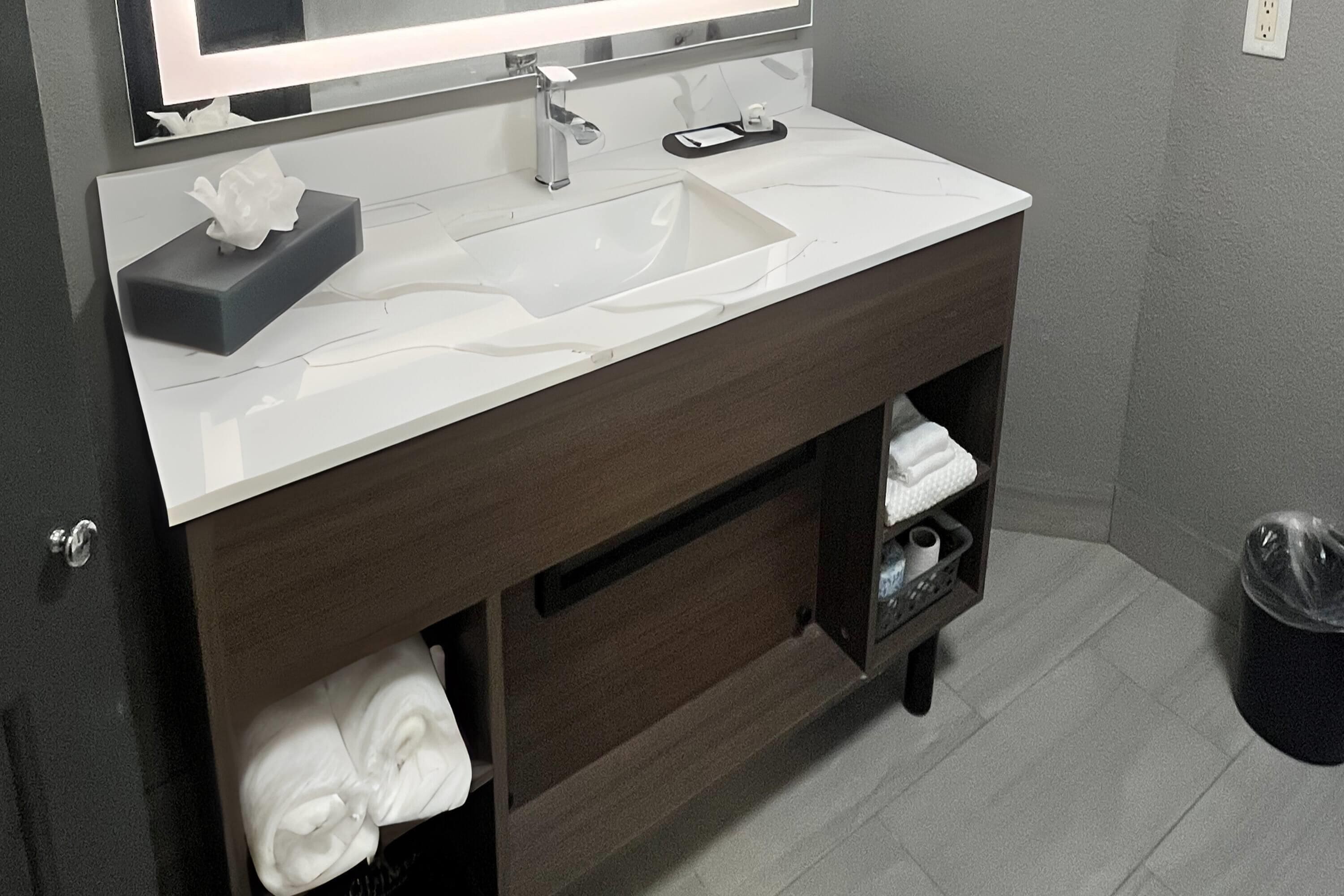 A modern bathroom with a white sink, dark wood vanity, and a mirror above.