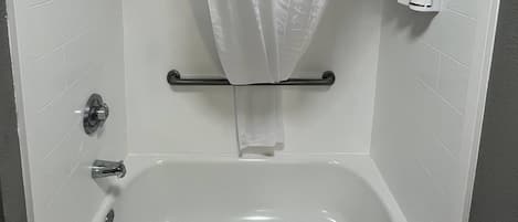 Un baño con bañera, cortina de ducha, toallero y artículos de aseo en un estante.