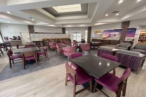 A modern hotel lobby with a central seating area, a reception desk, and a view of the cityscape. - La Quinta Inn & Suites by Wyndham Jacksonville Butler Blvd (Jacksonville)